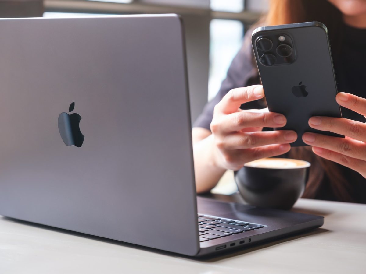 Someone working at a laptop with a phone in hand